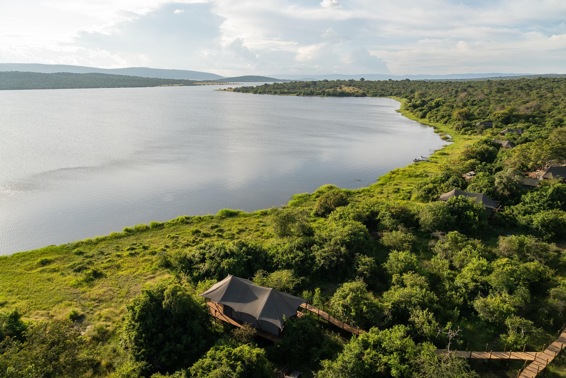 Luxusní safari chata s výhledem na africké jezero obklopené zelení.