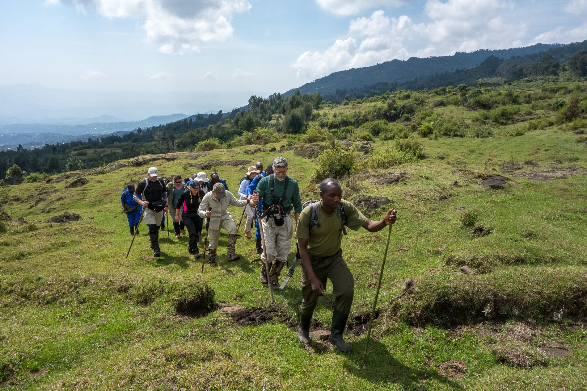 Skupina turistů na horském trekkingu v africkém prériu s hůlkami a batohy.